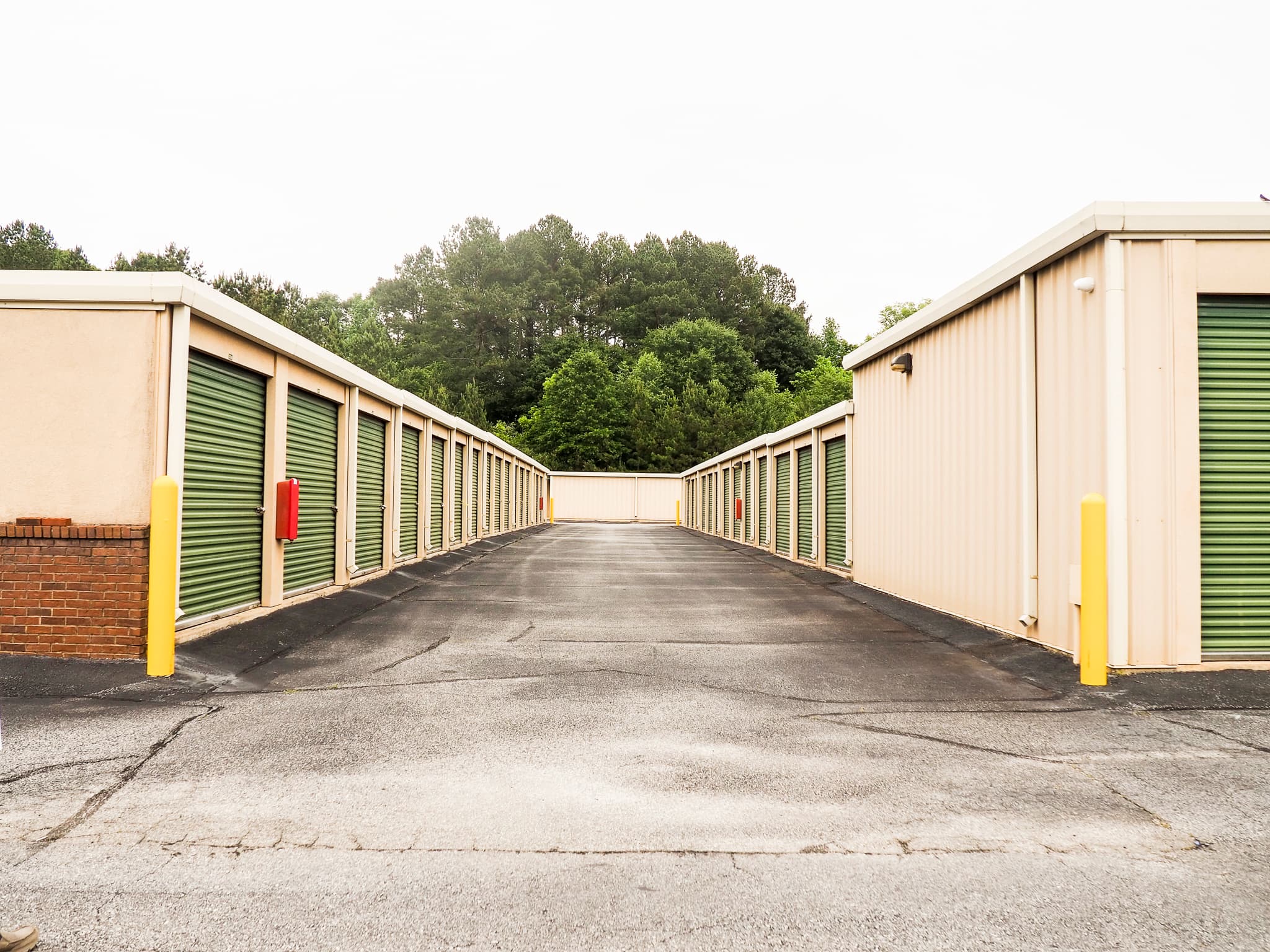 Drive aisle between rows of green roll-up storage doors at Crazy Ray's Self Storage